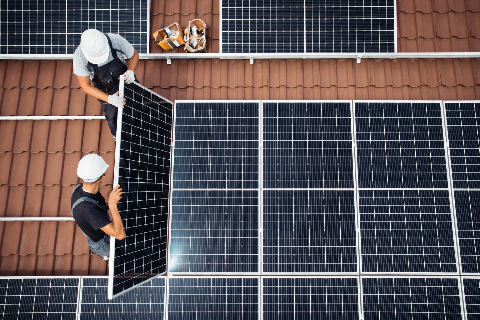 Due operatori posizionano un pannello fotovoltaico su un tetto in tegole